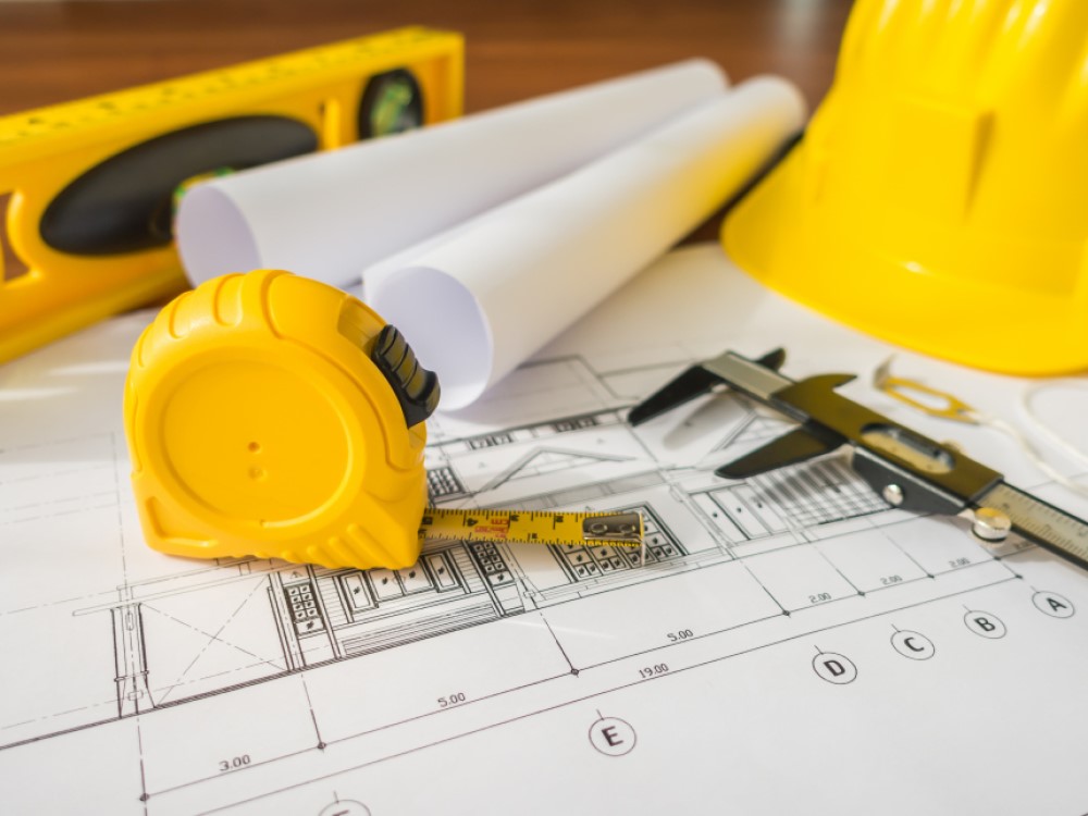 construction-plans-with-yellow-helmet-drawing-tools-bluep